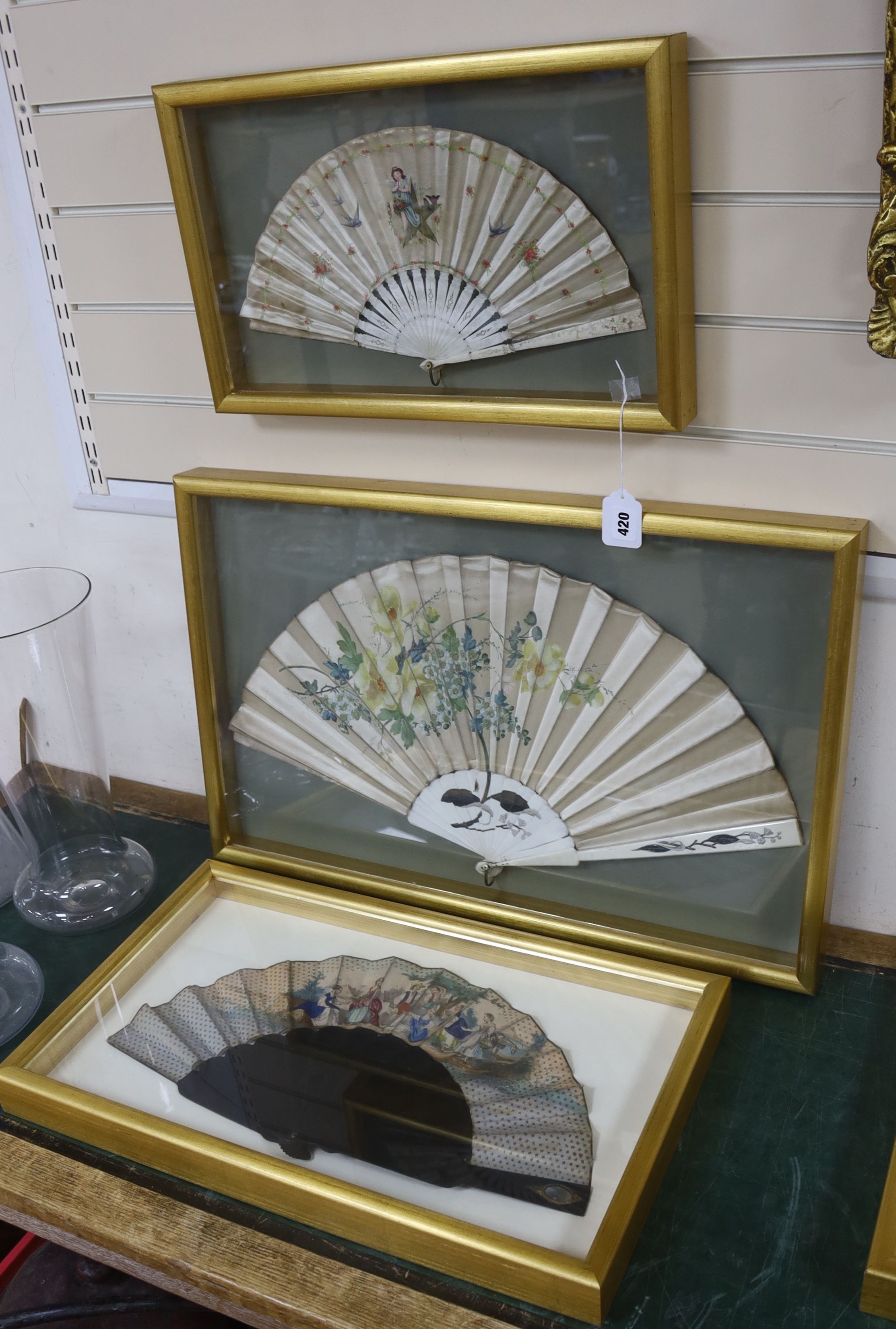 An early 19th century had tinted paper and ebony fan and two late 19th century ivory silk and bone fans, one painted with floral sprays, all three cased, largest case 46 x 71 cm (3)